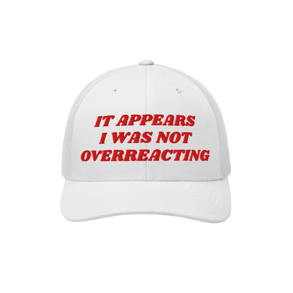 White mesh-back trucker cap, solid front with bold red embroidery: “IT APPEARS I WAS NOT OVERREACTING.” The Overreacting 