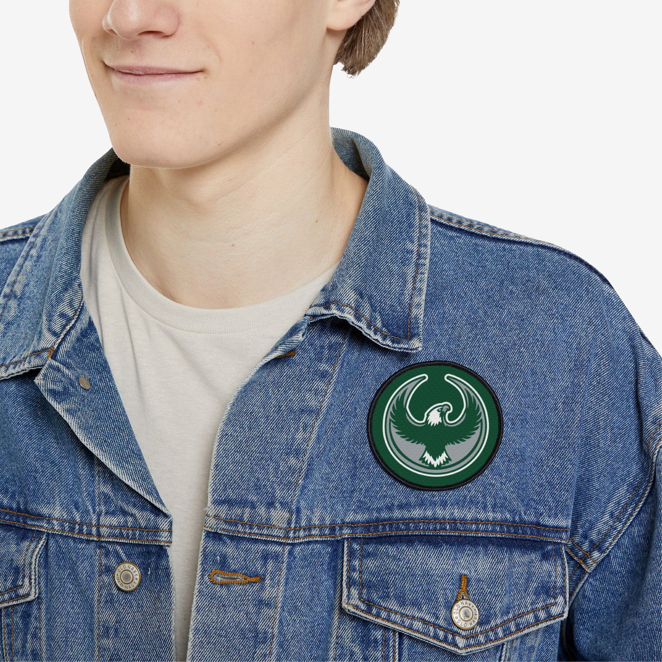 Person wearing a light-wash denim jacket adorned with the Philly Rebel Alliance Patch, featuring a green and gray eagle emblem, symbolizing anti-fascist energy and support for immigrant rights.