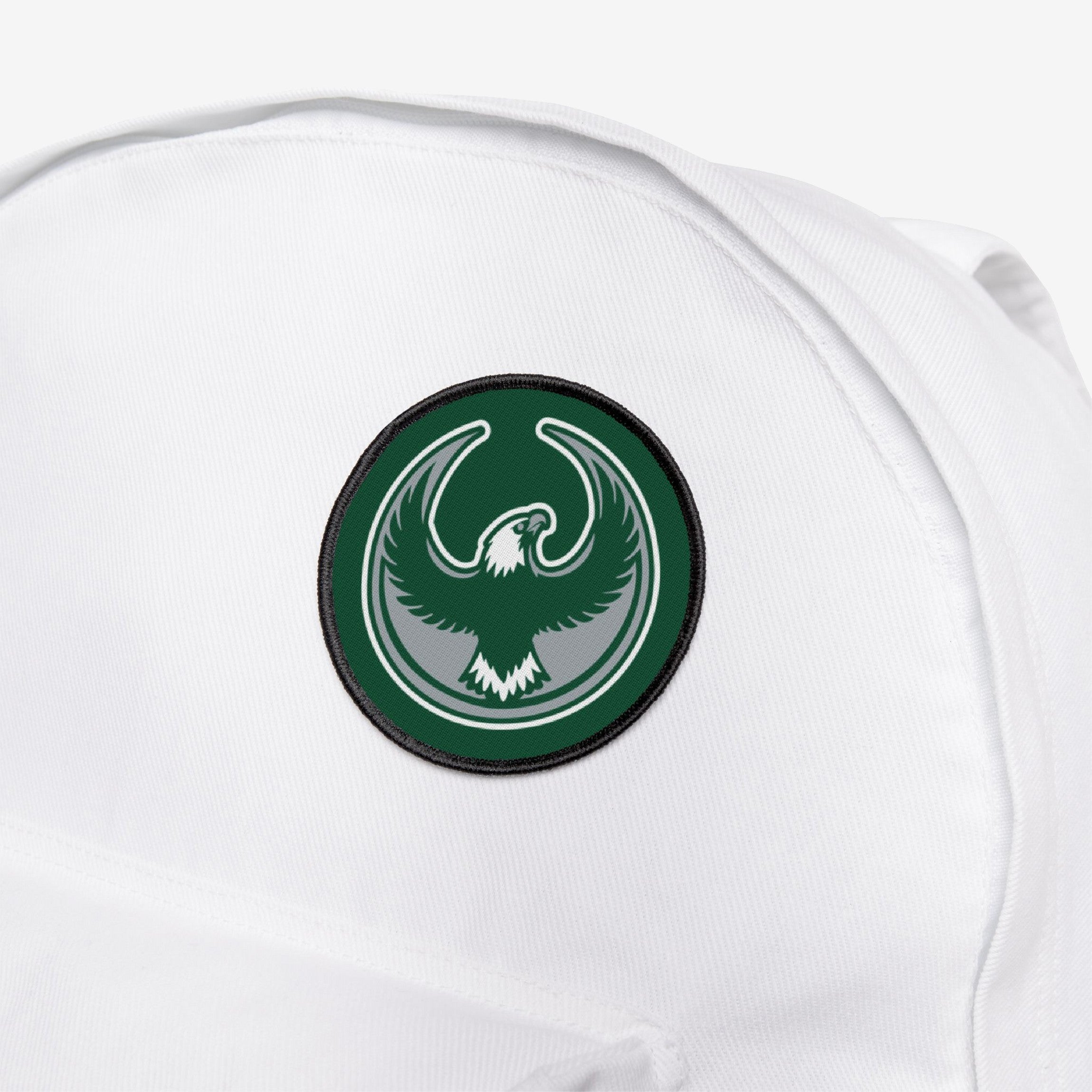 Philly Rebel Alliance Patch on a white backpack, featuring a stylized eagle in flight within a dark green circle, symbolizing anti-fascist protest energy and support for immigrant rights and equality.