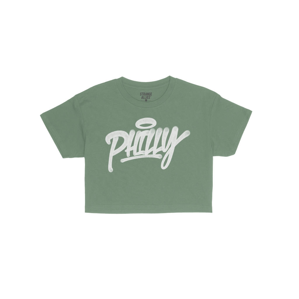 Philadelphia Handstyle Women's Baby Tee in bright green, featuring bold white graffiti-style PHILLY script with a halo, laid 