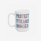 White ceramic Protect My Trans Homies mug with chunky hand-lettered slogan in trans pride colors, advocating for trans rights. A bold, loving statement for morning routines. Dishwasher-safe, available in 11 oz. and 15 oz. sizes.