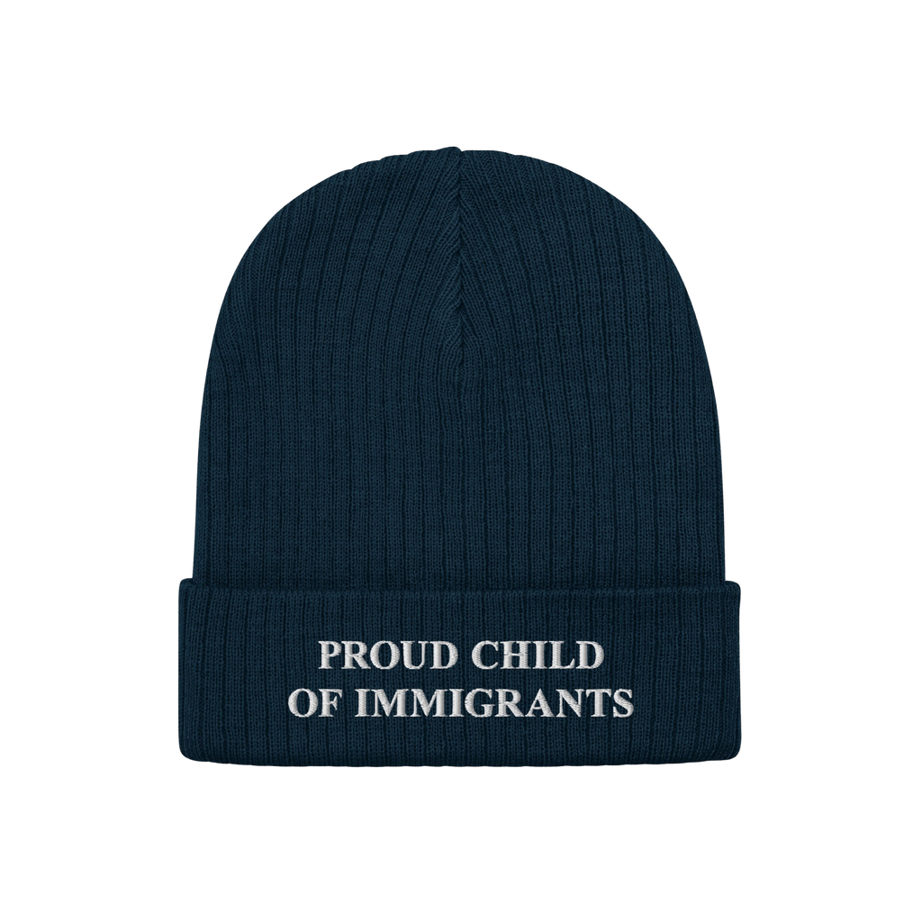 Navy-blue beanie with “PROUD CHILD OF IMMIGRANTS” in white embroidery on the cuff, symbolizing identity and heritage. The