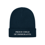 Navy-blue beanie with “PROUD CHILD OF IMMIGRANTS” in white embroidery on the cuff, symbolizing identity and heritage. The