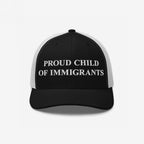 Black-and-white trucker cap with PROUD CHILD OF IMMIGRANTS embroidered on the front, symbolizing identity and heritage, echoing a message of resilience and pride.