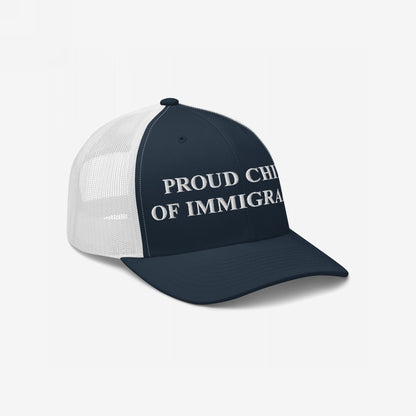 Trucker-style cap with navy front, white mesh back, and PROUD CHILD OF IMMIGRANTS embroidered in white block letters, symbolizing identity and resilience.