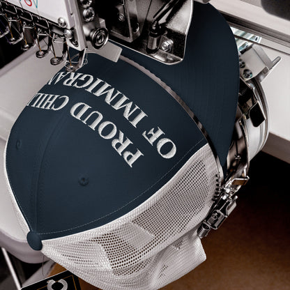 Proud Child of Immigrants Hat in embroidery setup, showcasing bold white stitching on navy, symbolizing heritage and resilience. The trucker cap combines minimalist style with a powerful identity statement.