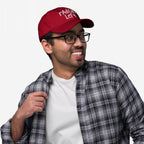Young man wearing the Radical Left Hat, a red baseball cap with embroidered white script, styled with black-framed glasses and a plaid shirt, embodying a progressive, justice-aligned fashion statement.
