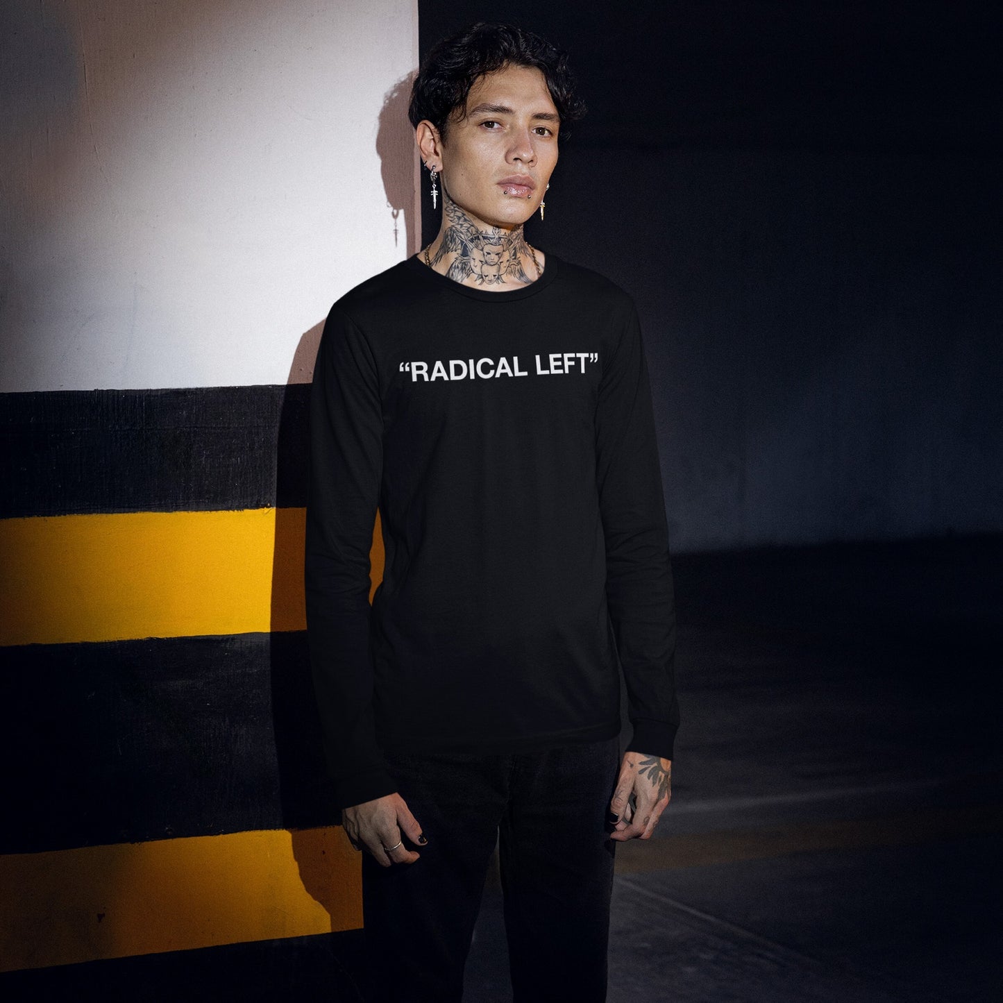 Young person in parking garage wearing Radical Left T-shirt, showcasing bold statement against societal norms. The black long-sleeved shirt features RADICAL LEFT in white, embodying satire and solidarity.