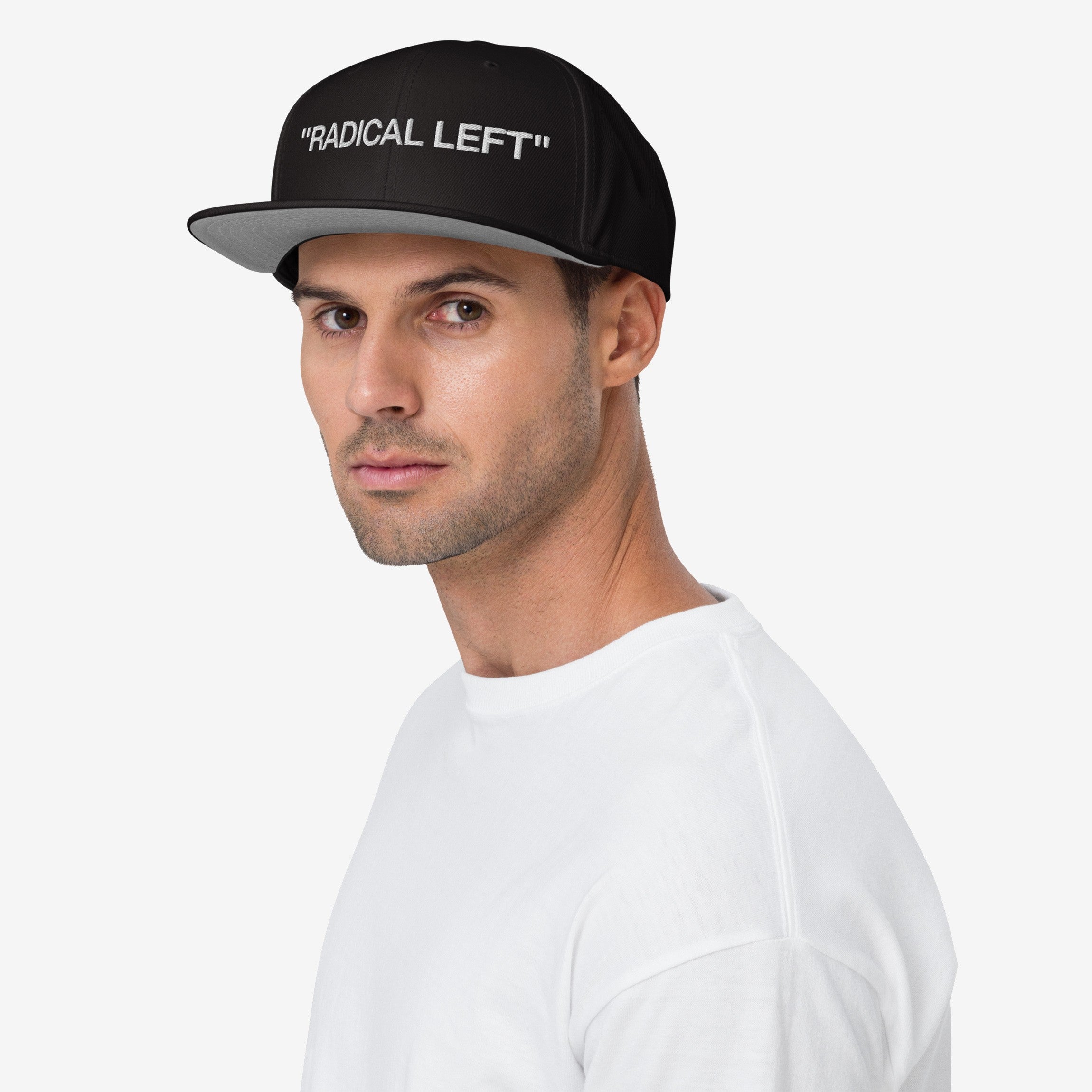 Young man in profile wearing the Radical Left Classic Hat, a black snapback with “RADICAL LEFT” embroidered in white, paired with a simple white crew-neck T-shirt, embodying bold, progressive style.