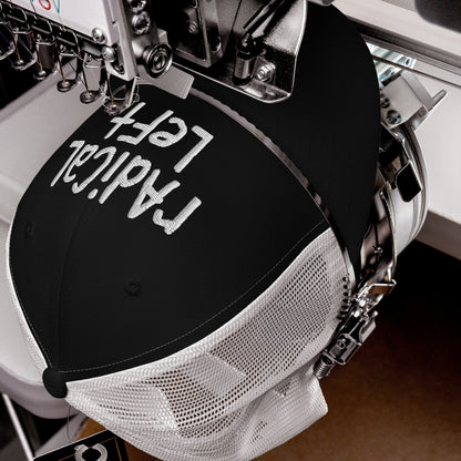 Close-up of an industrial embroidery machine stitching Radical Left in white thread on a black mesh-back trucker hat, symbolizing bold progressivism and a stand against fearmongering.