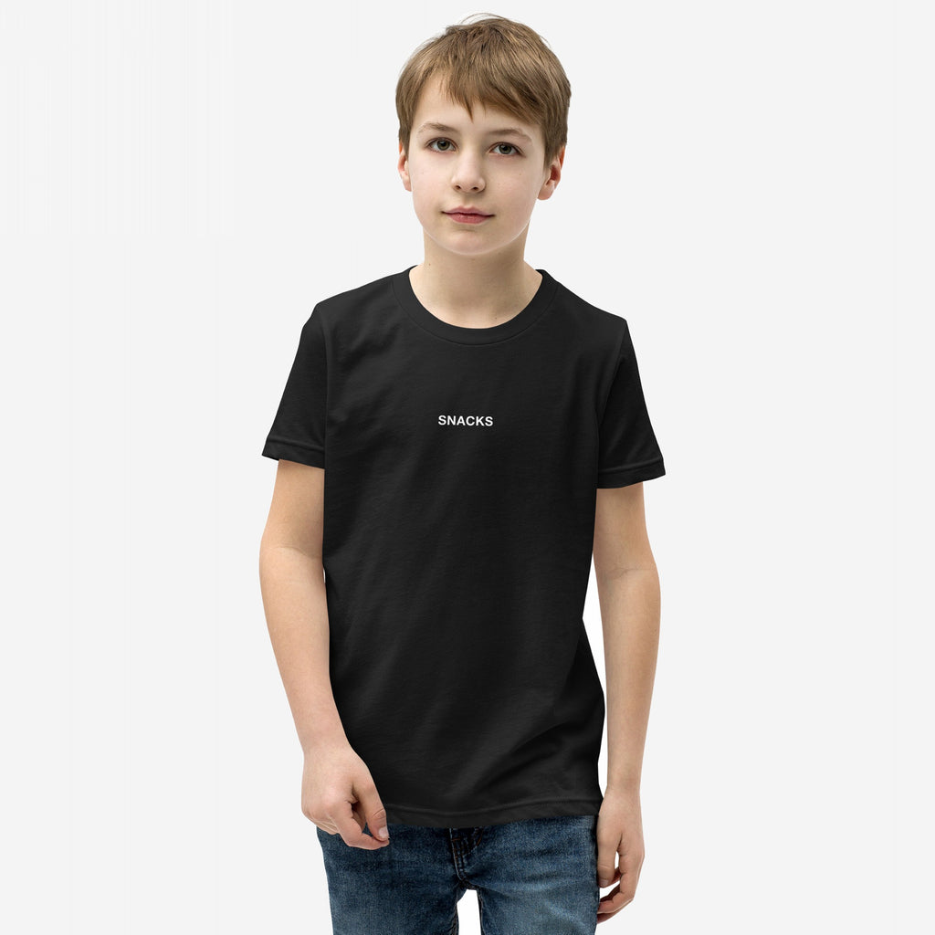 Young boy models the Snacks T-shirt, featuring subtle SNACKS text, embodying a playful, rebellious spirit. Perfect for every snack lover, it’s an enigmatic fashion statement for all ages.