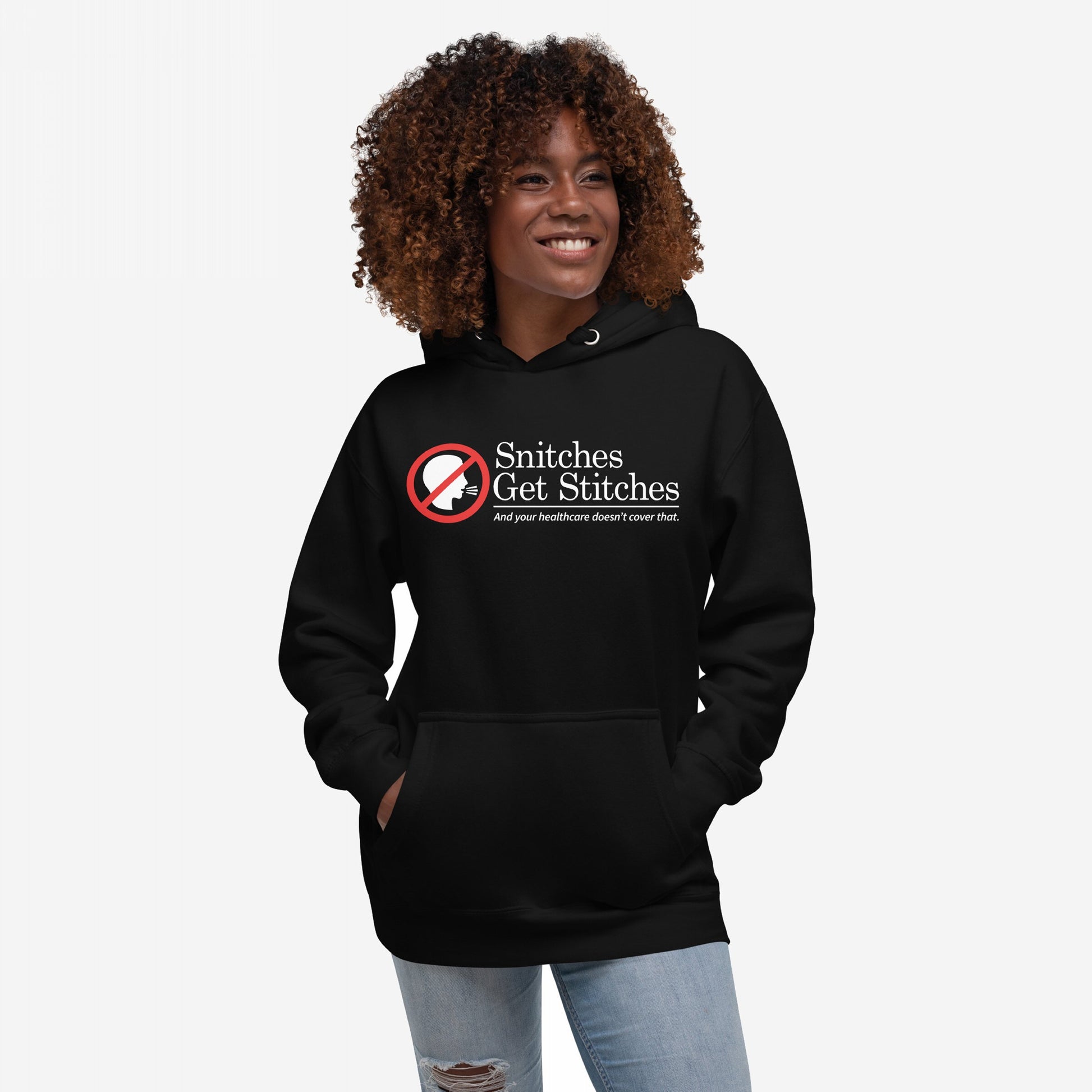Snitches Get Stitches Hoodie features a bold graphic of a no symbol over a whispering profile, with text mocking snitches and healthcare, worn by a smiling person with hands in the front pocket.