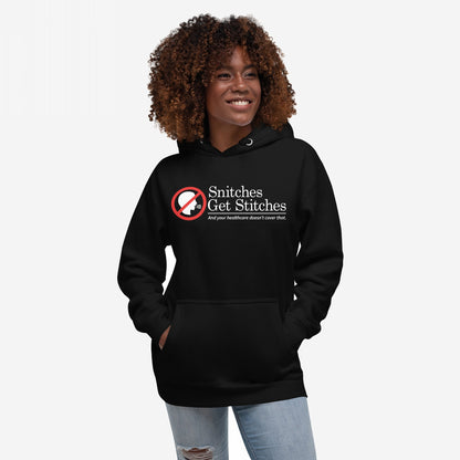 Snitches Get Stitches Hoodie features a bold graphic of a no symbol over a whispering profile, with text mocking snitches and healthcare, worn by a smiling person with hands in the front pocket.