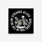 Social Club Giclée Print featuring two skeletons toasting with beer mugs, encircled by the phrase We're All in This Together, promoting inclusivity and camaraderie. Available in multiple square sizes.