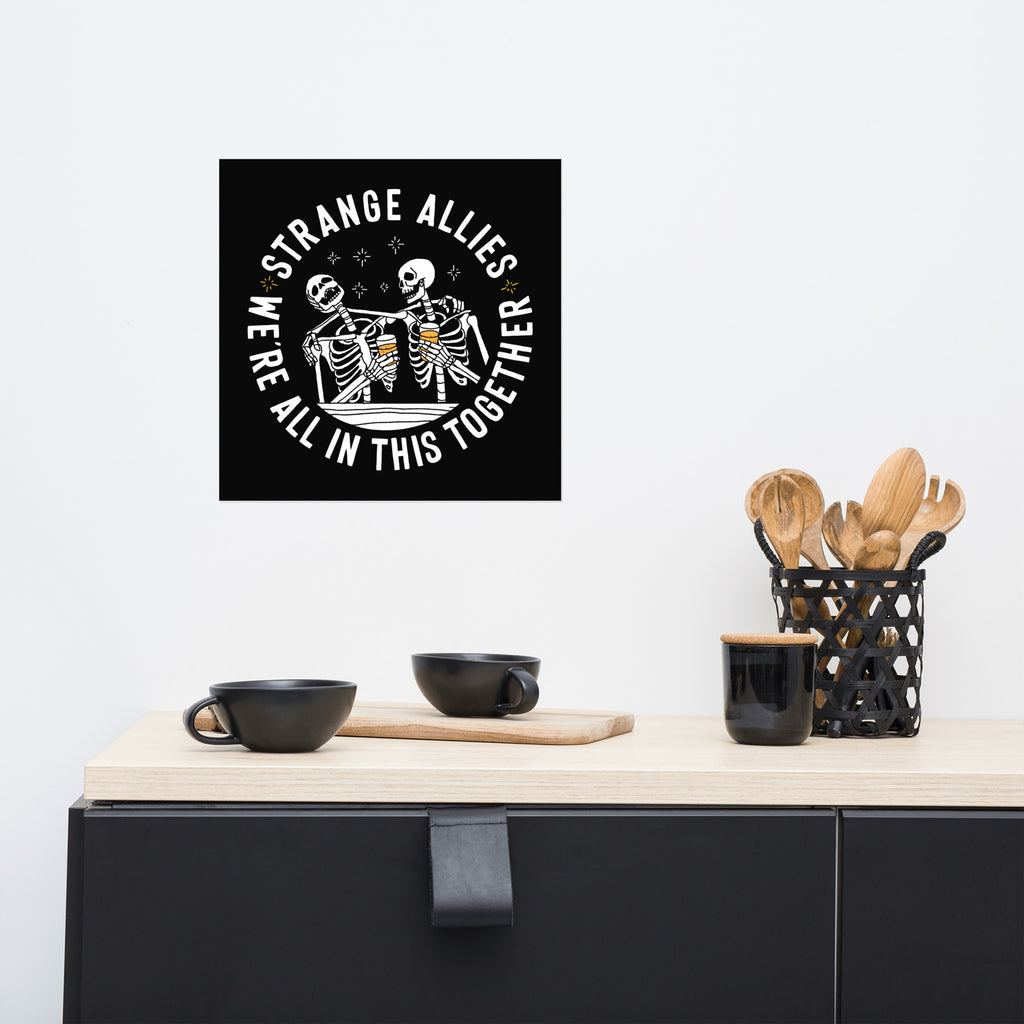 Social Club Giclée Print features two skeletons cheering with beer mugs, surrounded by the phrases STRANGE ALLIES and WE’RE ALL IN THIS TOGETHER, embodying unity and inclusivity.