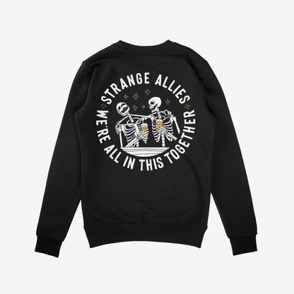 Social Club Hoodie & Sweatshirt featuring a back circular graphic of skeletons clinking beer mugs, with STRANGE ALLIES and WE’RE ALL IN THIS TOGETHER text, surrounded by star accents.