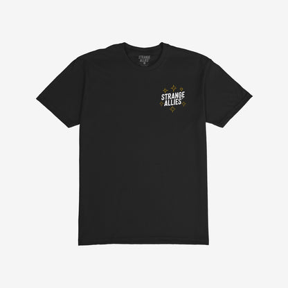 Social Club T-shirt features STRANGE ALLIES in white with gold starbursts on the front, celebrating unexpected friendships. Back showcases skeletons clinking glasses, embodying shared camaraderie and inclusivity.