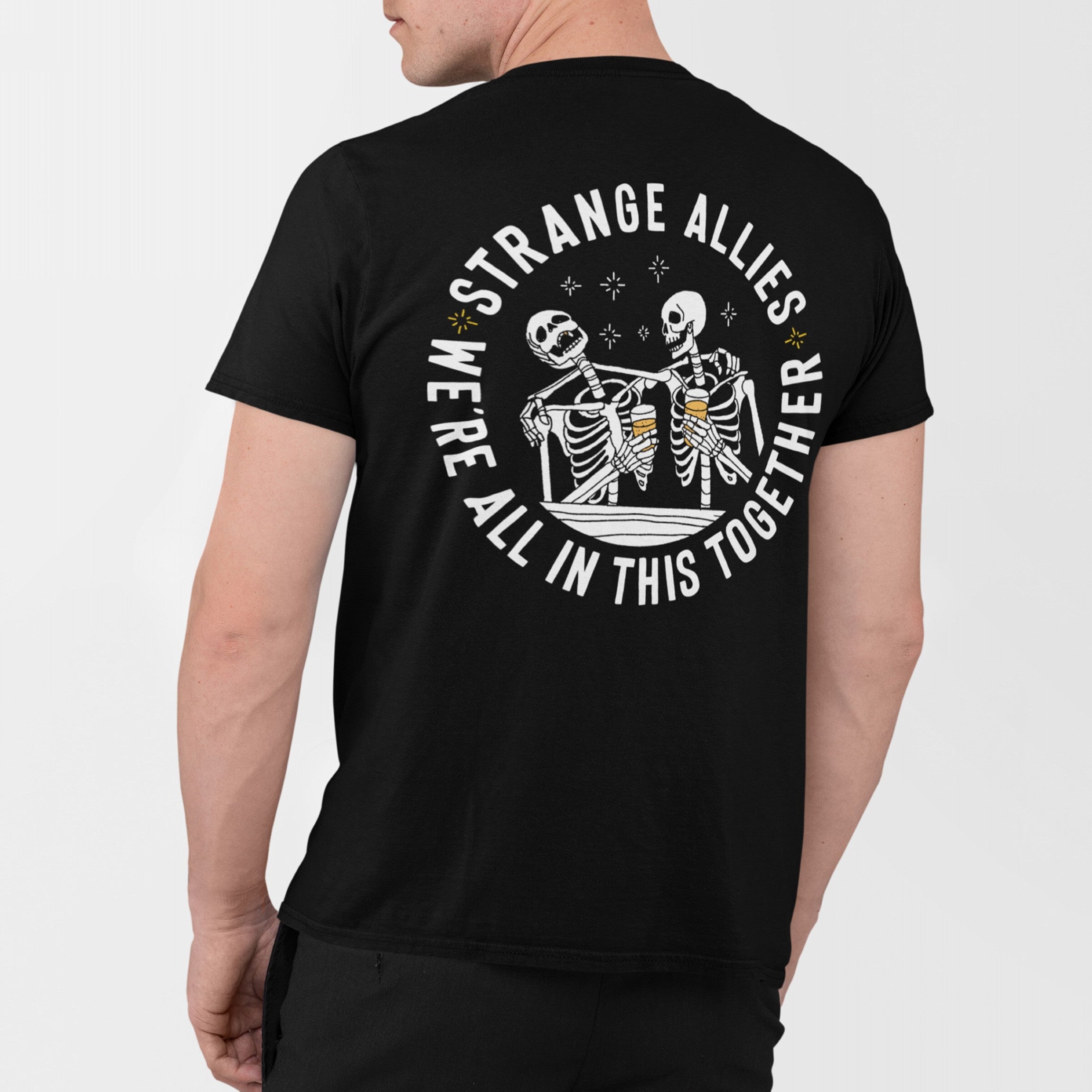 Social Club T-shirt back view, featuring two skeletons arm-in-arm with beers, encircled by “STRANGE ALLIES” and “WE’RE ALL IN THIS TOGETHER,” representing unity through shared humor and camaraderie.