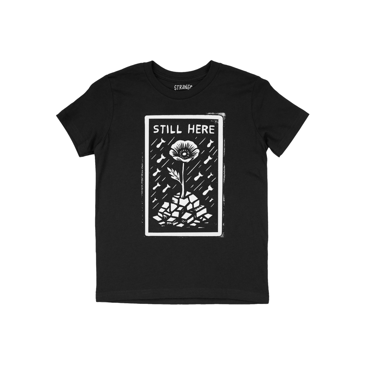 Still Here T-shirt features a bold white graphic of a flower emerging from rubble with bombs falling, symbolizing resilience 