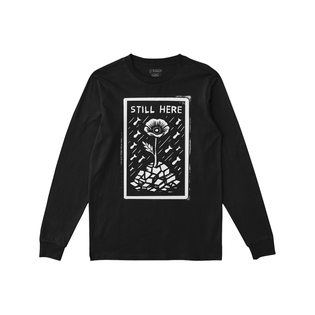 Still Here T-shirt features a striking protest design with 'STILL HERE' text above a single flower growing from rubble, symbo