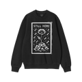 Still Here JULZ Hoodie & Sweatshirt displays a flower emerging from rubble amid falling raindrops, symbolizing resilience and