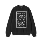 Still Here JULZ Hoodie & Sweatshirt displays a flower emerging from rubble amid falling raindrops, symbolizing resilience and