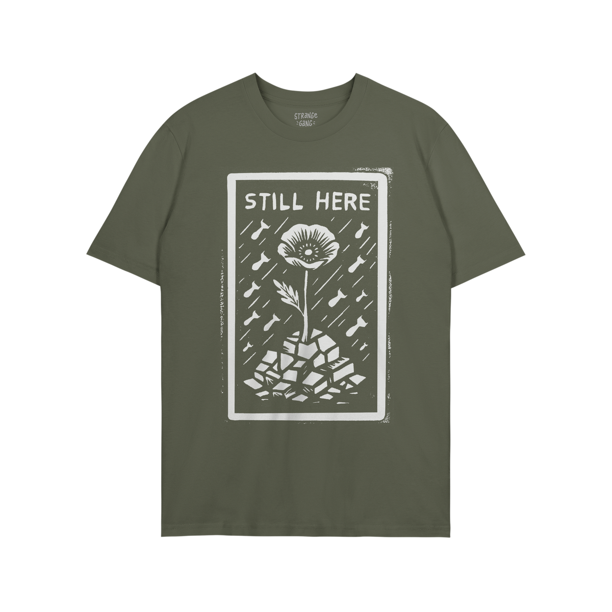 Still Here T-shirt features a bold graphic of a flower rising through rubble with bombs falling, symbolizing resilience and p