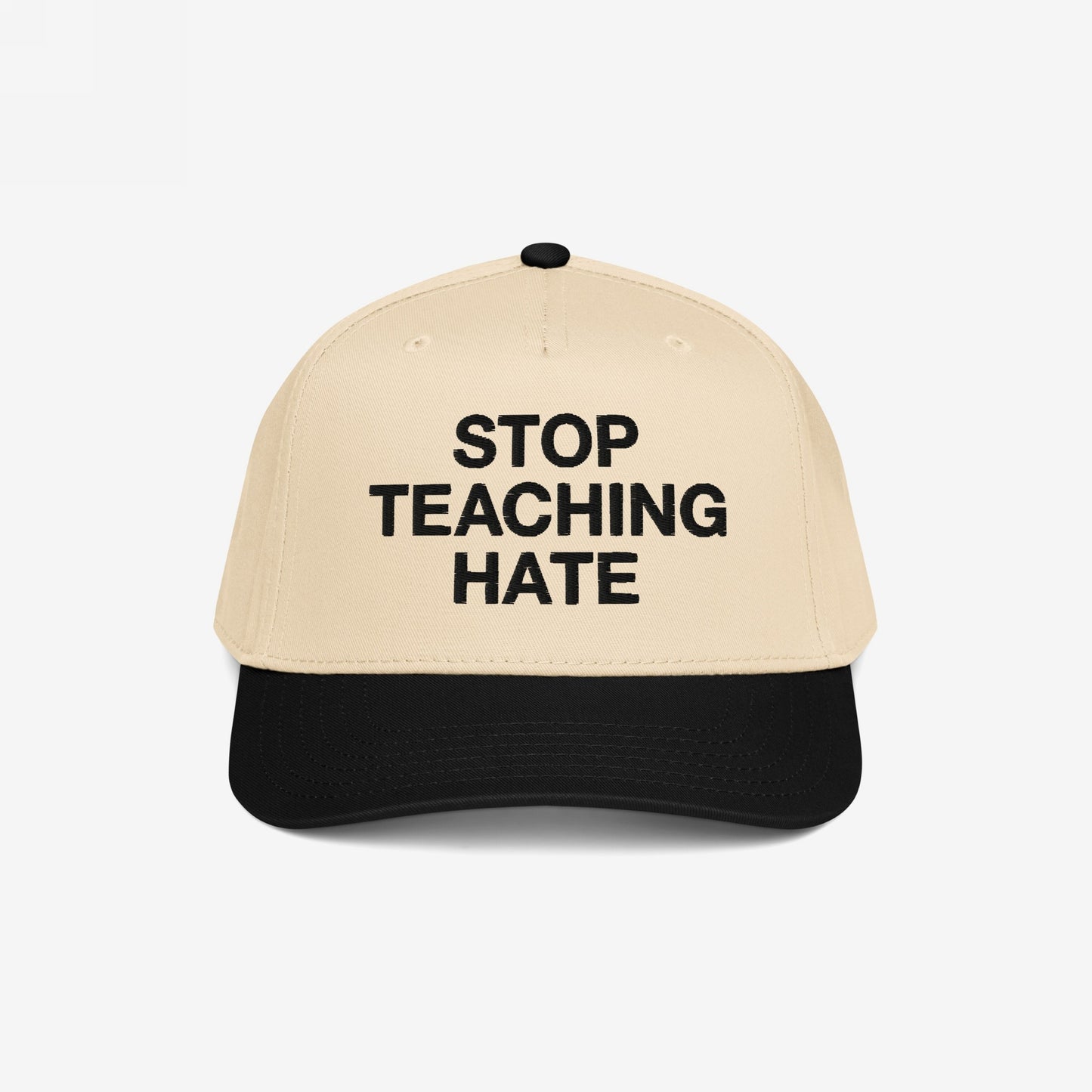 Two-tone baseball cap with a beige crown and black bill, featuring “STOP TEACHING HATE” in bold black letters, symbolizing a commitment to equality and a stance against bigotry.