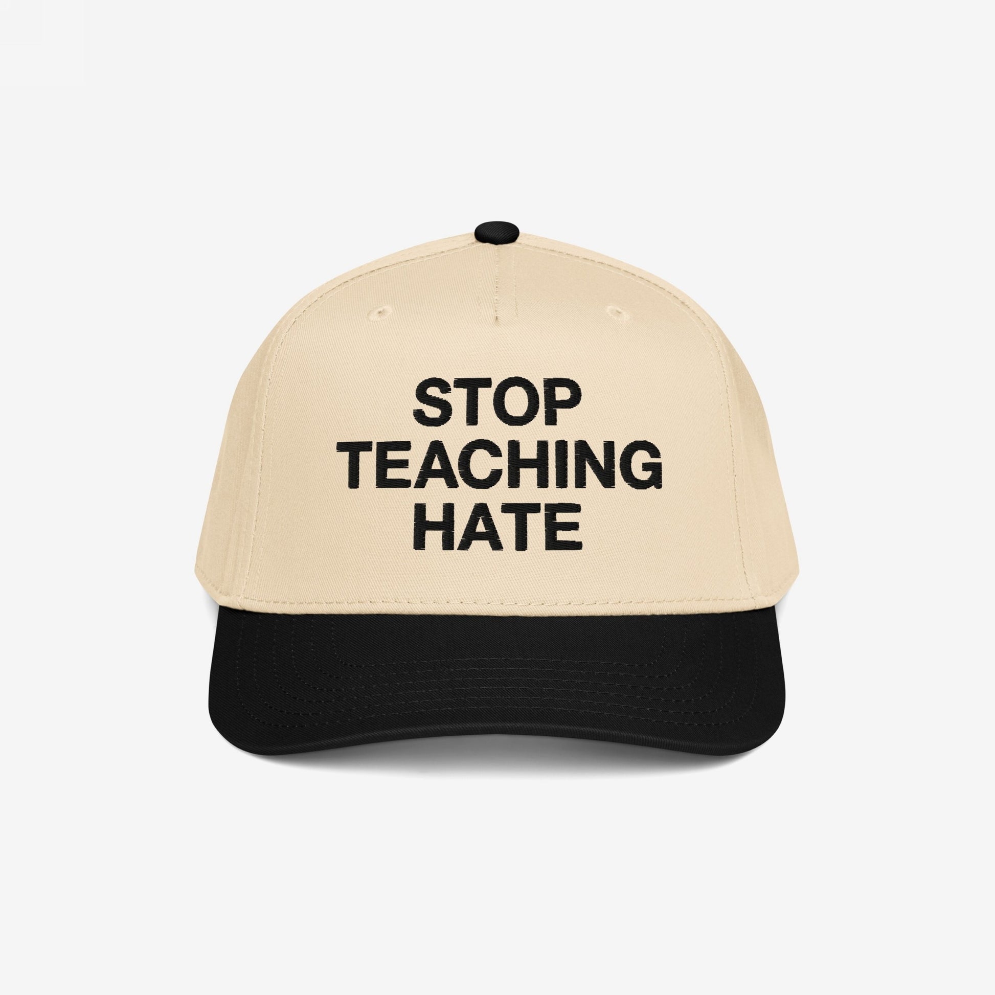 Two-tone baseball cap with a beige crown and black bill, featuring “STOP TEACHING HATE” in bold black letters, symbolizing a commitment to equality and a stance against bigotry.
