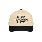 Two-tone baseball cap with a beige crown and black bill, featuring “STOP TEACHING HATE” in bold black letters, symbolizin