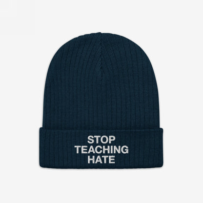 Dark navy-blue, rib-knit winter beanie with folded cuff featuring the bold slogan STOP TEACHING HATE in white lettering, embodying a strong visual protest against hate and promoting equality.