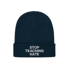 Dark navy-blue, rib-knit winter beanie with folded cuff featuring the bold slogan STOP TEACHING HATE in white lettering, embo