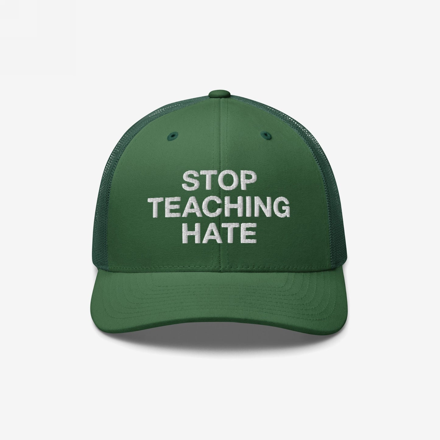 Dark green trucker-style cap with STOP TEACHING HATE boldly embroidered in white on the front, symbolizing a stand against bigotry and promoting equality.