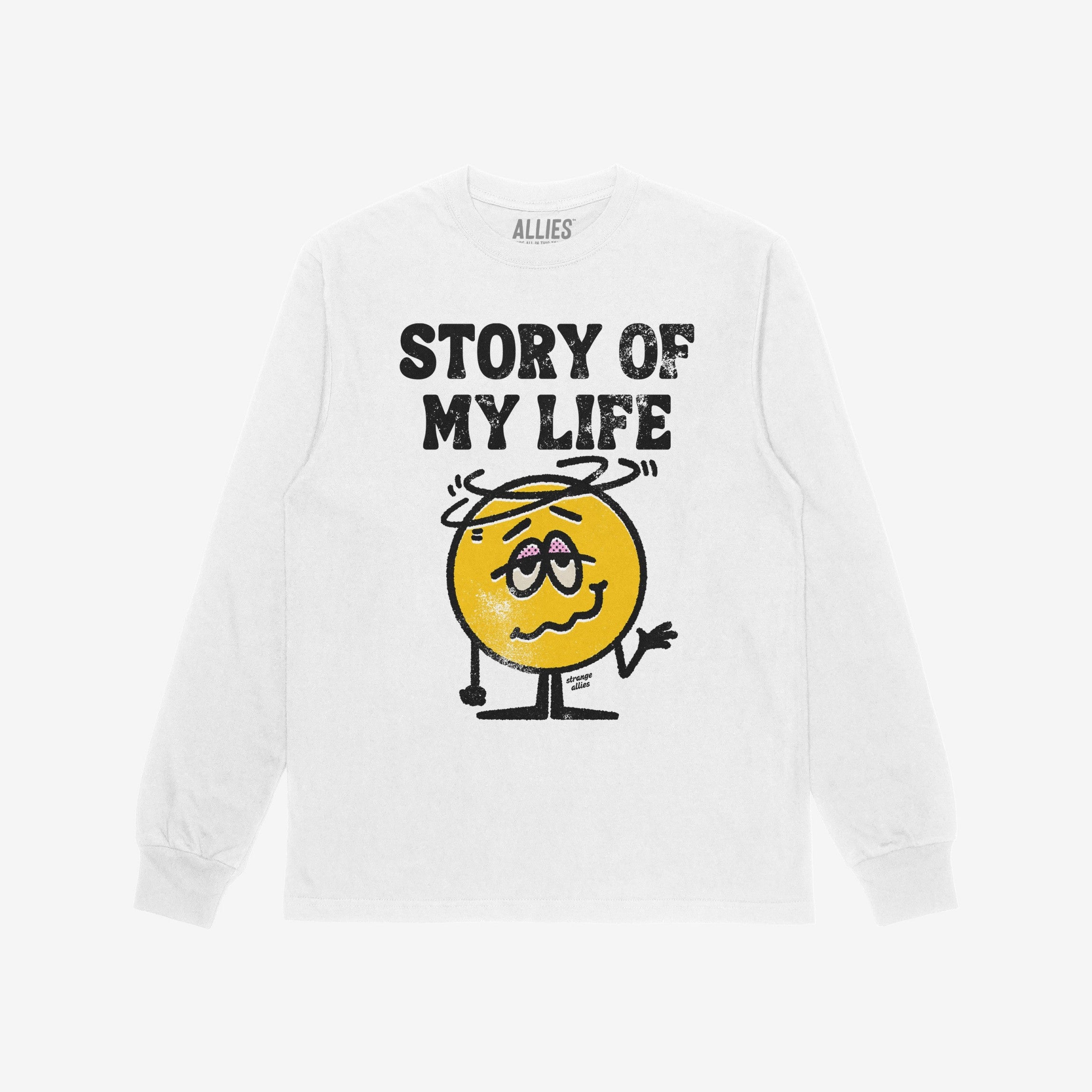 Story Of My Life Shirt features a distressed print with black lettering and a dazed yellow smiley, capturing life's chaos humorously. A tiny strange allies signature adds a unique touch.