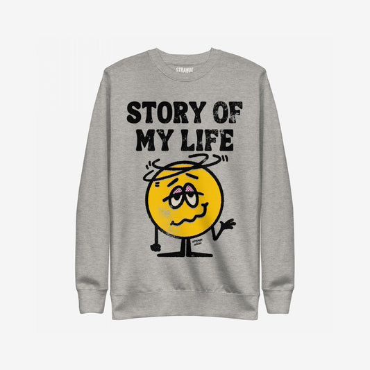 Story Of My Life Sweatshirt featuring a dazed cartoon smiley with droopy eyelids and shrugging arms under bold text, capturing a humorous take on life's mishaps.