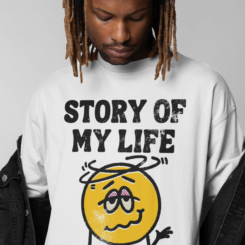 Person reveals Story Of My Life T-shirt featuring a dizzy cartoon face, symbolizing chaos and frustration. Embrace life's mishaps with humor while supporting mental health awareness through NAMI.