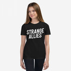 Young woman models the Strange Allies T-shirt with bold STRANGE ALLIES™ text, embodying a statement of inclusivity and individuality, reflecting the ethos of embracing outsiders and supporting equality.