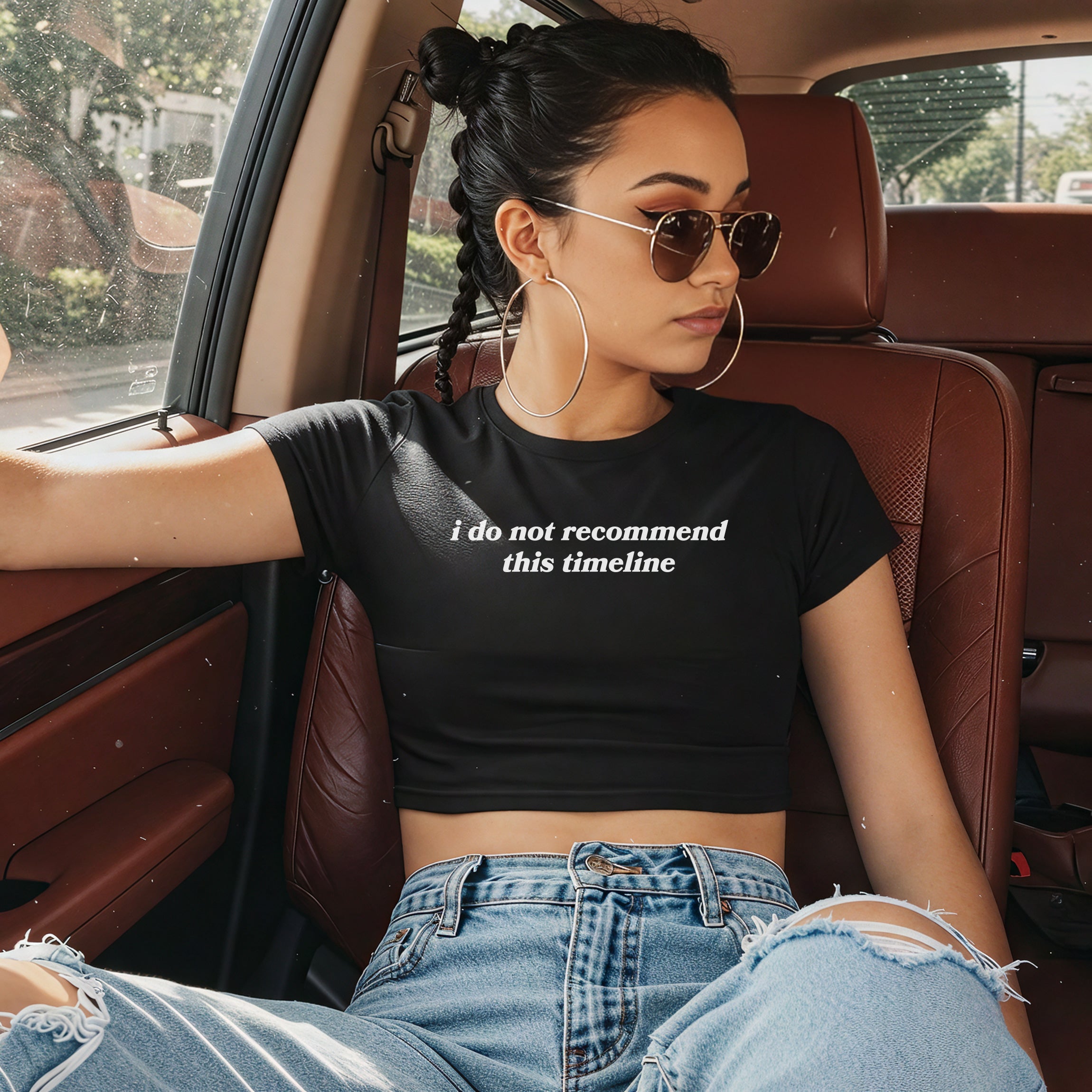A young woman wears the Timeline Women's Baby Tee, featuring the phrase i do not recommend this timeline, paired with light-wash ripped jeans and aviator sunglasses, lounging in a car's leather interior.