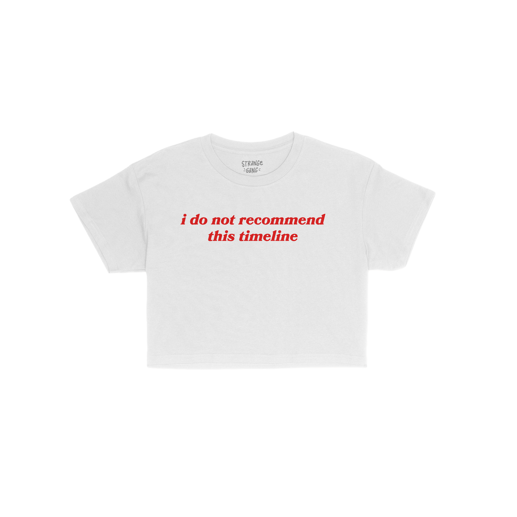 Timeline Women's Baby Tee features bold red text, i do not recommend this timeline, on a cropped white T-shirt, reflecting mi