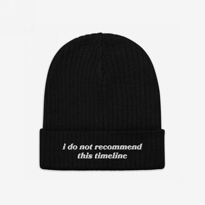 A black rib-knit beanie, the Timeline Hat, features i do not recommend this timeline embroidered on its cuff, embodying a sarcastic stance against current events.