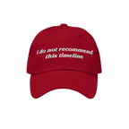 Red six-panel baseball cap with white embroidery reading “i do not recommend this timeline”. Ideal for political humor en