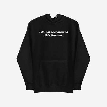 The Timeline Hoodie features a black pullover with I do not recommend this timeline in white serif text across the chest, capturing a sharp, minimalist style with a touch of sarcasm.