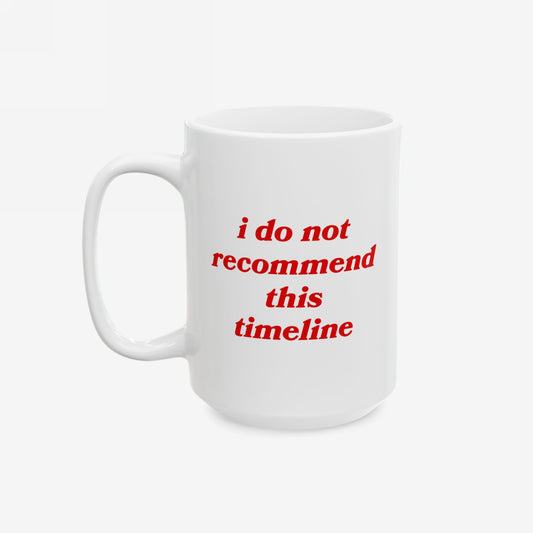 White ceramic mug with red text, I Do Not Recommend This Timeline, capturing a satirical reflection on societal challenges. Dishwasher-safe, available in 11 oz. and 15 oz., with a standard C-handle.