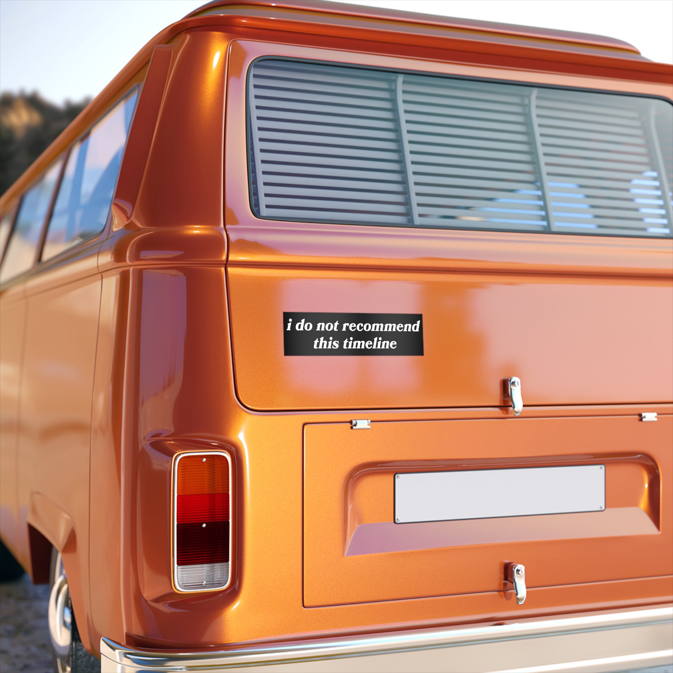 The rear of a burnt-orange vintage van displays the “Timeline Sticker & Magnet” featuring the phrase “I do not recommend this timeline” in black-and-white, adjacent to the tail light assembly.