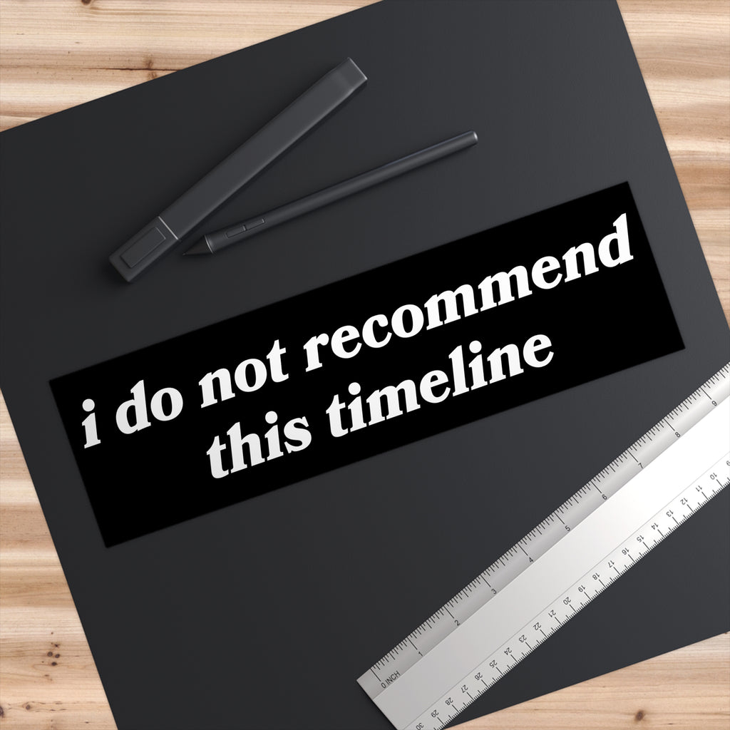 Timeline Sticker & Magnet on a dark desk mat, featuring the phrase “i do not recommend this timeline.” Ideal for expressing existential humor, suited for various surfaces, symbolizing resilience amid chaos.