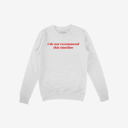 White crewneck sweatshirt featuring i do not recommend this timeline in red, reflecting humor and critique. Ideal for skeptics and realists, supporting mental health awareness through NAMI donations.
