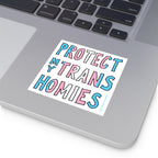 Protect My Trans Homies Sticker & Magnet on a silver laptop corner, showcasing hand-drawn letters in trans pride colors, promoting visibility and advocacy for trans rights with all-weather durability.