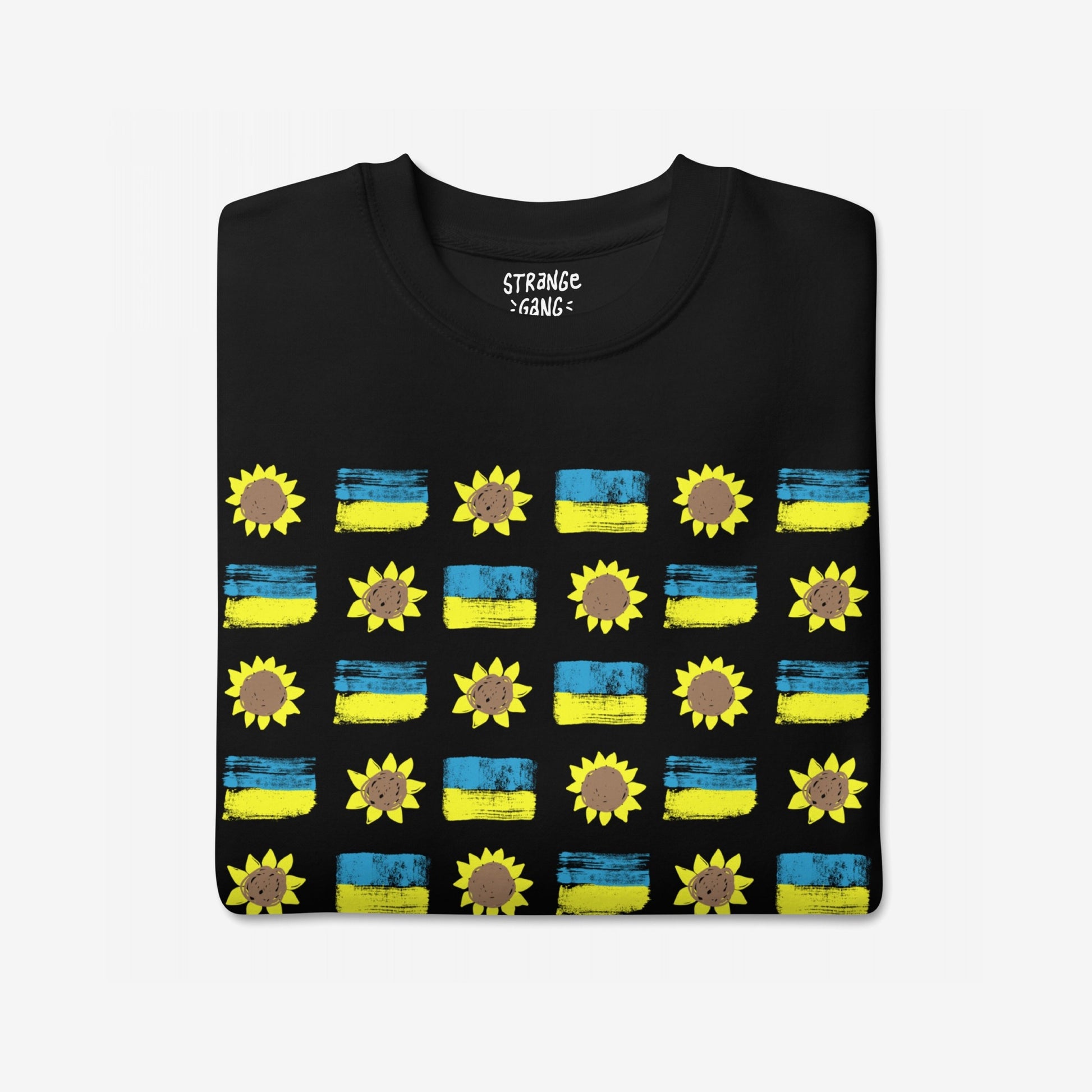 Ukraine Sunflowers Sweatshirt features a grid pattern of blue-yellow flags and sunflowers, symbolizing unity and courage. The folded black T-shirt highlights resilience and solidarity in support of Ukraine.