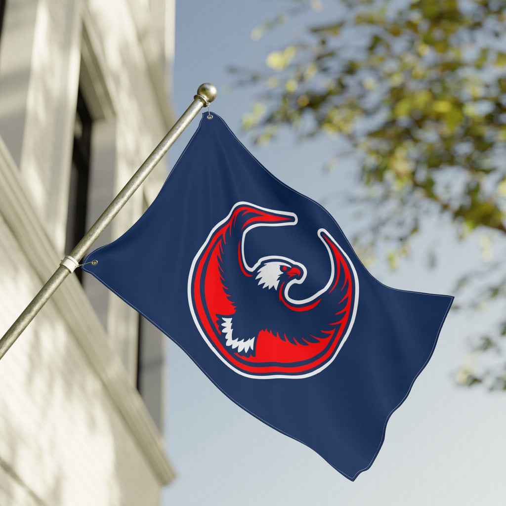 USA Rebel Alliance Flag featuring a stylized eagle emblem on a blue background, mounted on a metal pole in front of a building, symbolizing solidarity and resistance.