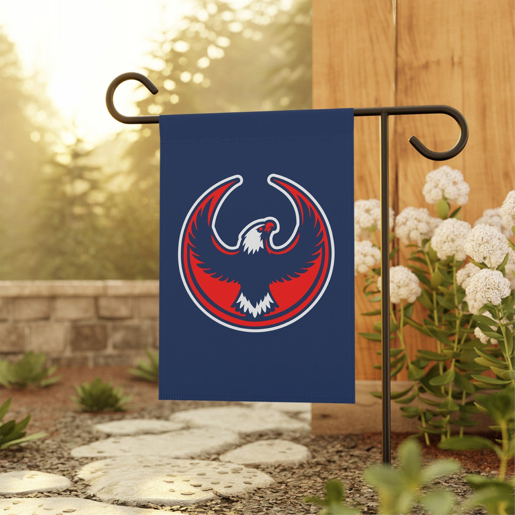 USA Rebel Alliance Garden Flag featuring a stylized eagle emblem, symbolizing anti-fascist and pro-community values, displayed on a black metal stand amidst a landscaped garden setting.